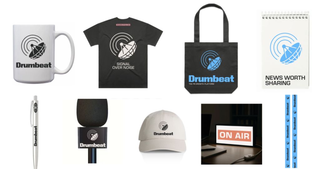 Drumbeat in objects: the mug, the mic flag, the ON AIR light, and a notepad that says news worth sharing.
